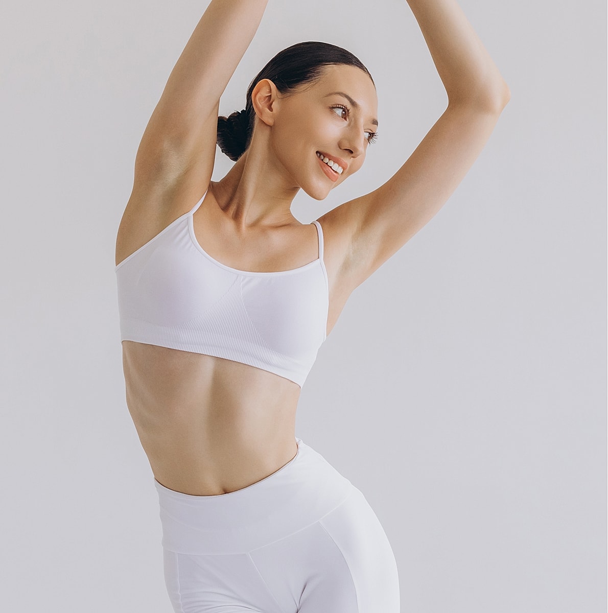 Smiling woman in white athletic wear posing joyfully.