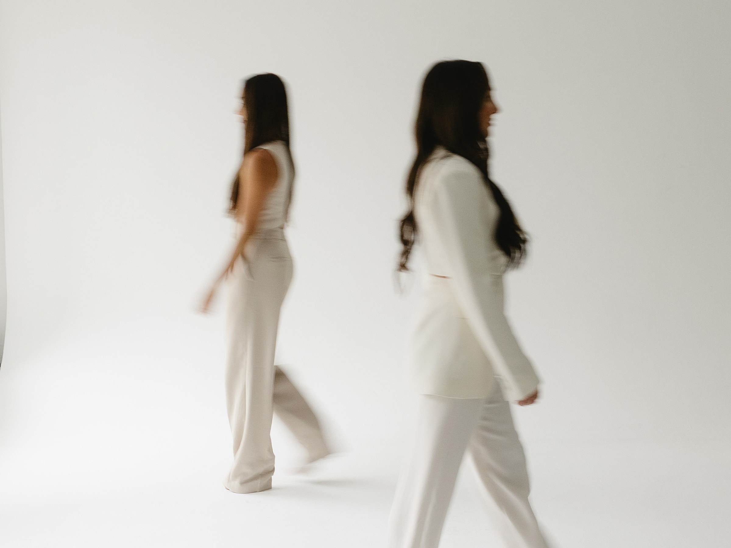 Two women walking in white outfits.